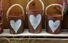 four buckets with hearts painted on them are sitting on a wooden shelf next to purple flowers