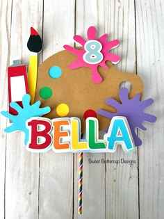 a wooden sign that says,'bella'and is decorated with colorful paper cutouts