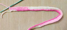 crocheted pink and white piece of cloth with green knitting needles next to it