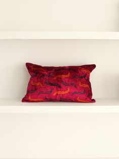 a red pillow sitting on top of a white shelf