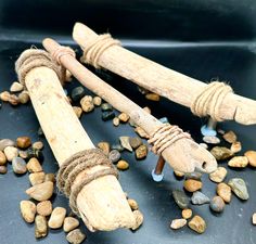 two pieces of driftwood with rope on top of rocks and gravel scattered around them