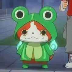 a green frog with big eyes standing next to a person in a red and white outfit