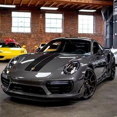 three different colored sports cars parked in a parking garage, one is black and the other is silver