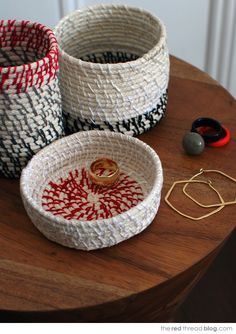 three woven baskets sitting on top of a wooden table next to earring hooks and earrings