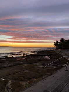 the sun is setting over the ocean and beach