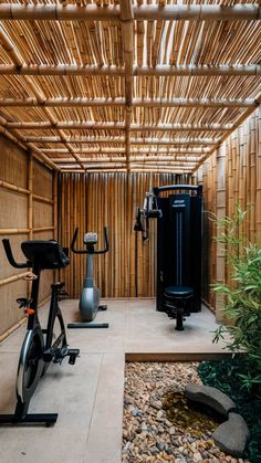 an indoor gym with exercise bikes and water features in the bamboo wall, surrounded by stones