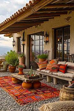 an outdoor patio with potted plants and rugs on the ground next to it