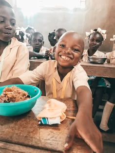 two young children sitting at a table with food in front of them and smiling for the camera