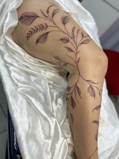 a woman's legs with tattoos on them and leaves in the middle of her leg