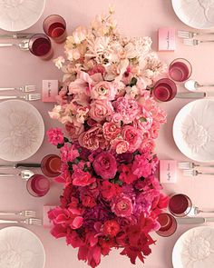 the table is set with pink flowers and plates