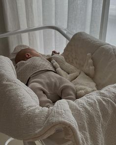 a baby sleeping in a crib with a stuffed animal on it's back