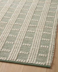 a green and white rug on top of a wooden floor next to a wood floor