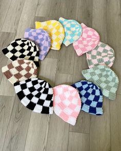 several knitted hats are arranged in a circle on the floor, all different colors