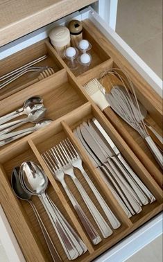 an open drawer with silverware and utensils in it