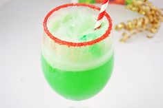 a green drink with a straw in it on a white table next to gold decorations