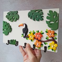 a person holding up a paper cut out of leaves and flowers with a toucan on it