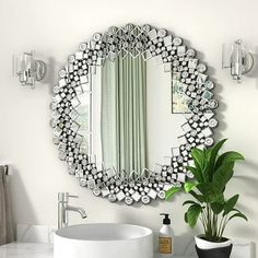 a white sink sitting under a large mirror next to a potted plant on top of a counter