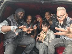 a group of people sitting in the back of a pick up truck with their hands out