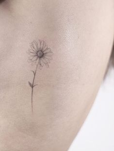 a woman's stomach with a single flower tattoo on her back side ribcage