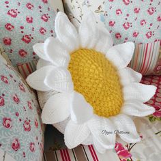 a crocheted sunflower sitting on top of pillows