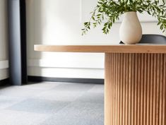 a vase filled with green plants sitting on top of a wooden table