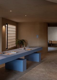 an empty room with two blue benches and a potted plant on the table in front of it