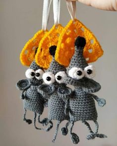 three crocheted mice hanging from a string with eyes on them and two hands holding the strings