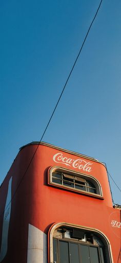 an orange building with a coca cola sign on it's side and power lines in the background