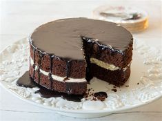 a chocolate cake on a white plate with one slice cut out and ready to be eaten