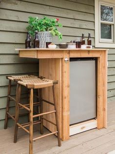 an outdoor bar with two stools on the front porch, next to a potted plant