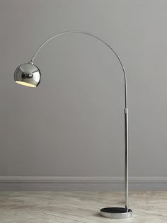 a lamp that is on top of a wooden floor in front of a gray wall