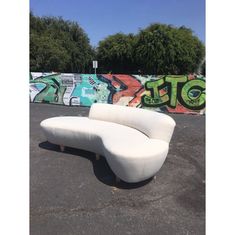 a white couch sitting in front of a graffiti covered wall