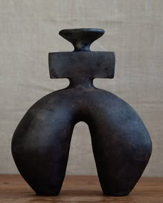 a black vase sitting on top of a wooden table