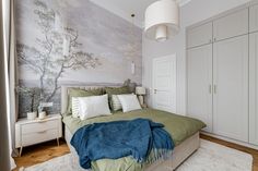 a bedroom with a large bed and wallpaper on the walls, along with white cupboards