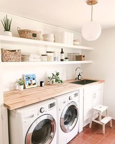 a washer and dryer in a small room with shelves above the washer