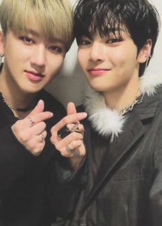 two young men standing next to each other with their fingers in the shape of v