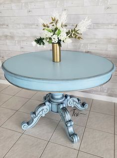 a blue table with white flowers in a vase on top