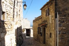 an alley way with cobblestone stone buildings and a street lamp in the distance