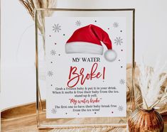 a sign with a santa hat on it sitting next to a vase filled with feathers