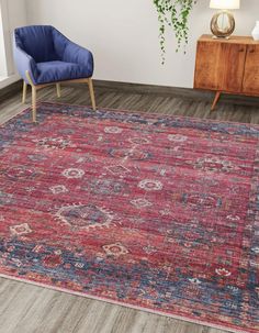 a red rug with blue and pink designs on the floor next to a blue chair