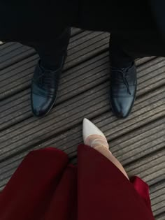 two people standing next to each other on a wooden floor with one person wearing white shoes