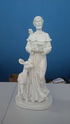 a statue of jesus holding a lamb on top of a white table next to a blue wall