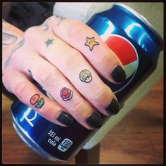 a woman's hand with tattoos holding a can of pepsi drink and her finger tattoo