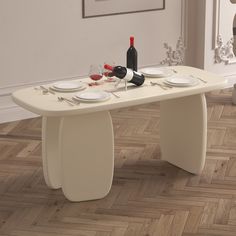 a dining table with plates and wine bottles on it in front of a white wall