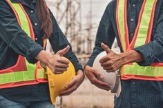 two construction workers giving thumbs up to each other