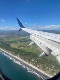 an airplane wing flying over the ocean and land