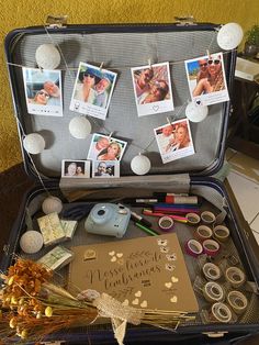 an open suitcase filled with pictures and other items on top of a table next to a wall