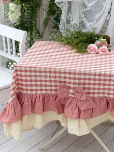 a red and white checkered table cloth with pink flowers on it next to a bench