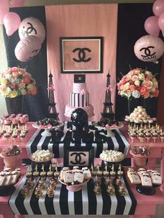 a pink and black dessert table at a paris themed birthday party with balloons, chanel cake, cupcakes, and candy