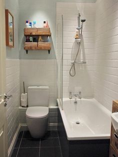 a white toilet sitting next to a bath tub in a bathroom under a light fixture